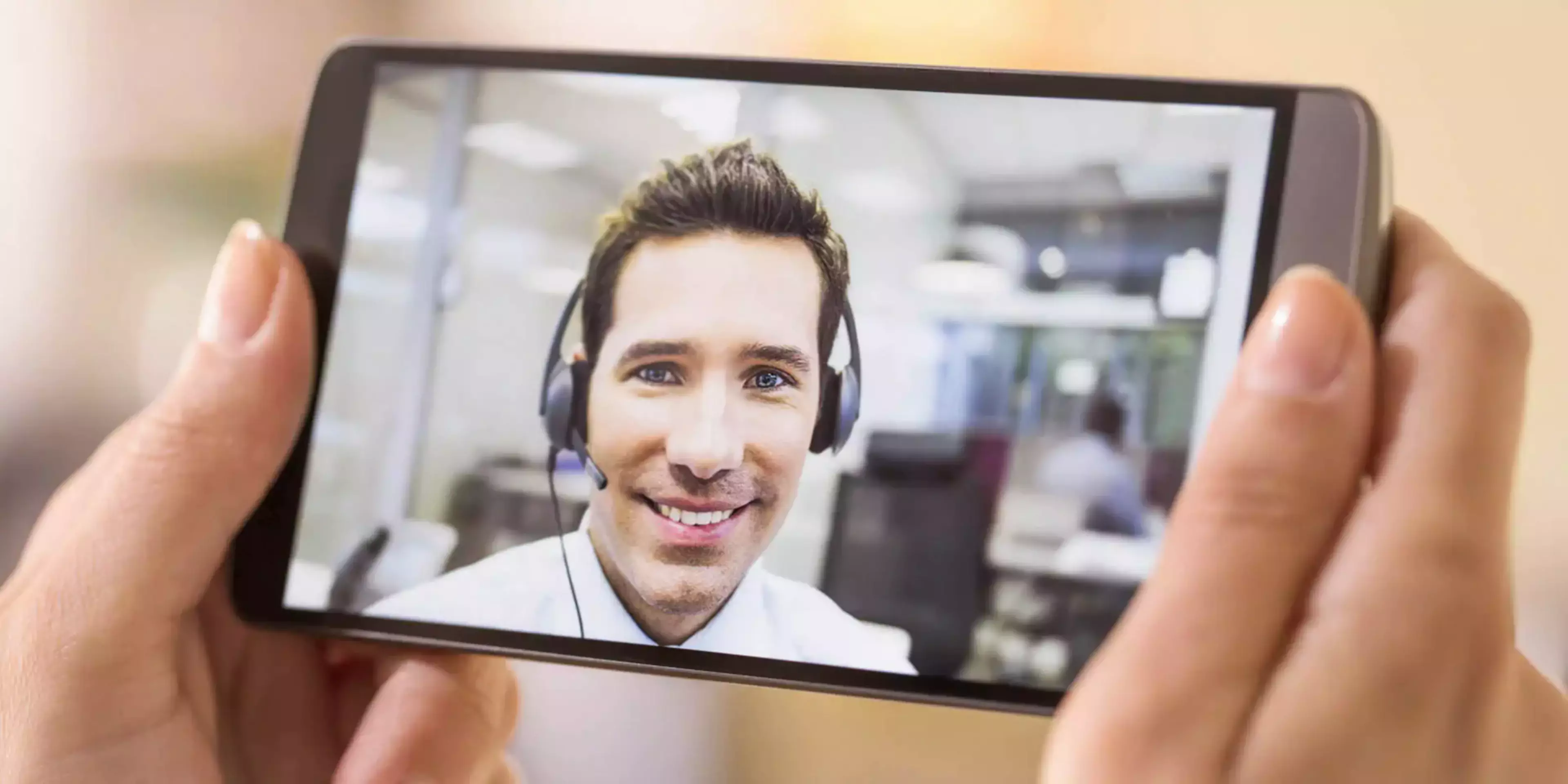 Person i videosamtale på mobil med headset, som illustrerer fjernsupport og remote IT-hjelp