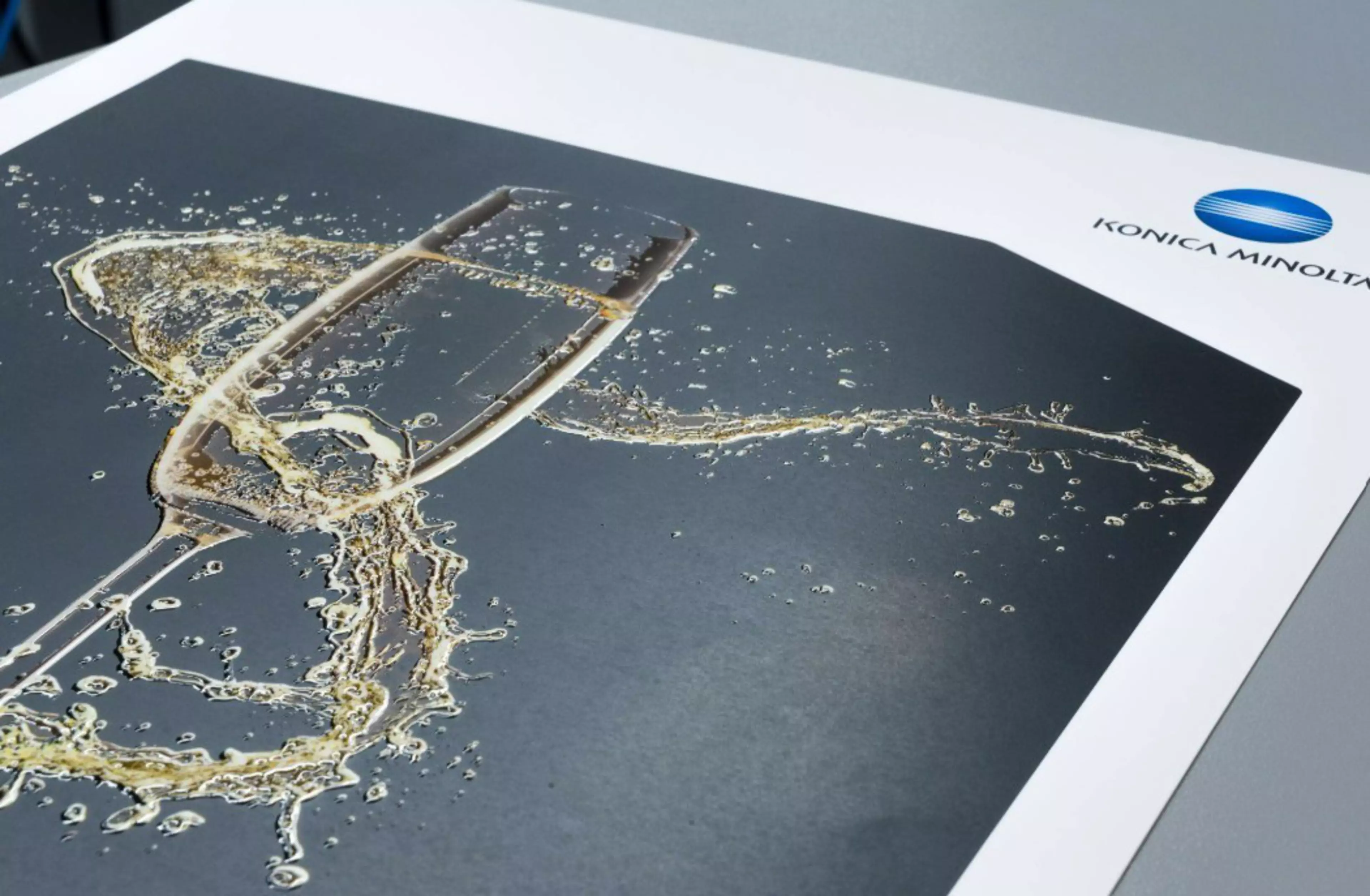 Print sample for embellishment featuring gold foil details, including a champagne glass design, with the Konica Minolta logo visible in the corner.