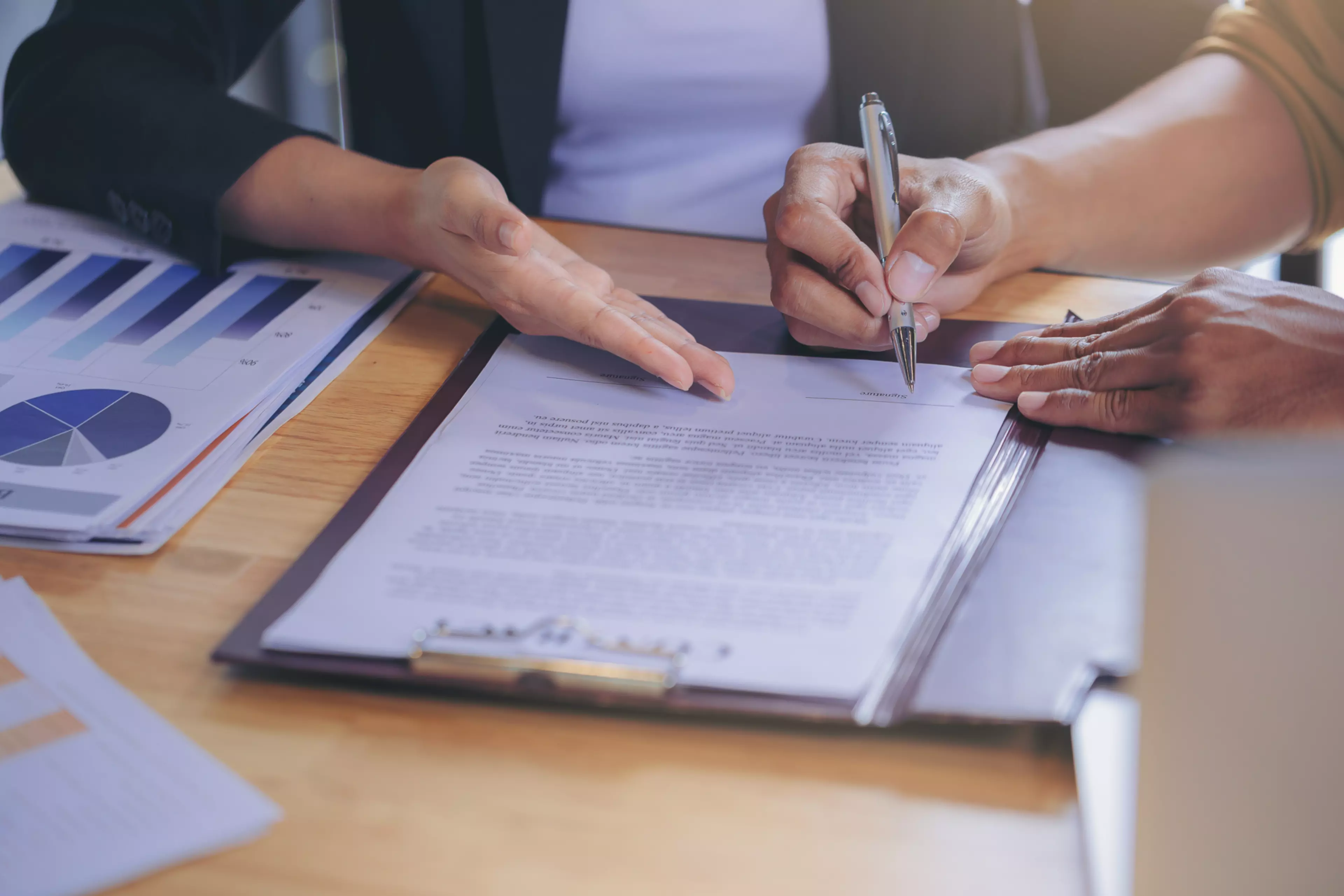 Las manos de dos personas trabajan sobre un documento