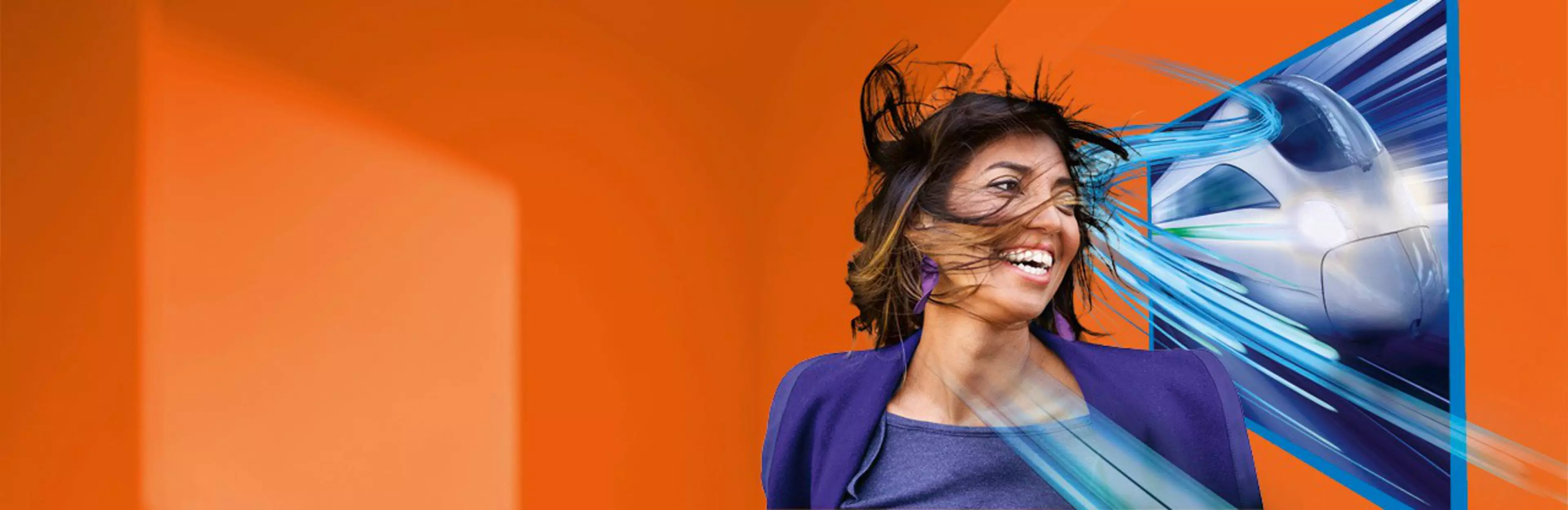 Una mujer sonriente sobre un fondo color naranja deja que su pelo se mueva por el aire que levanta un tren de alta velocidad