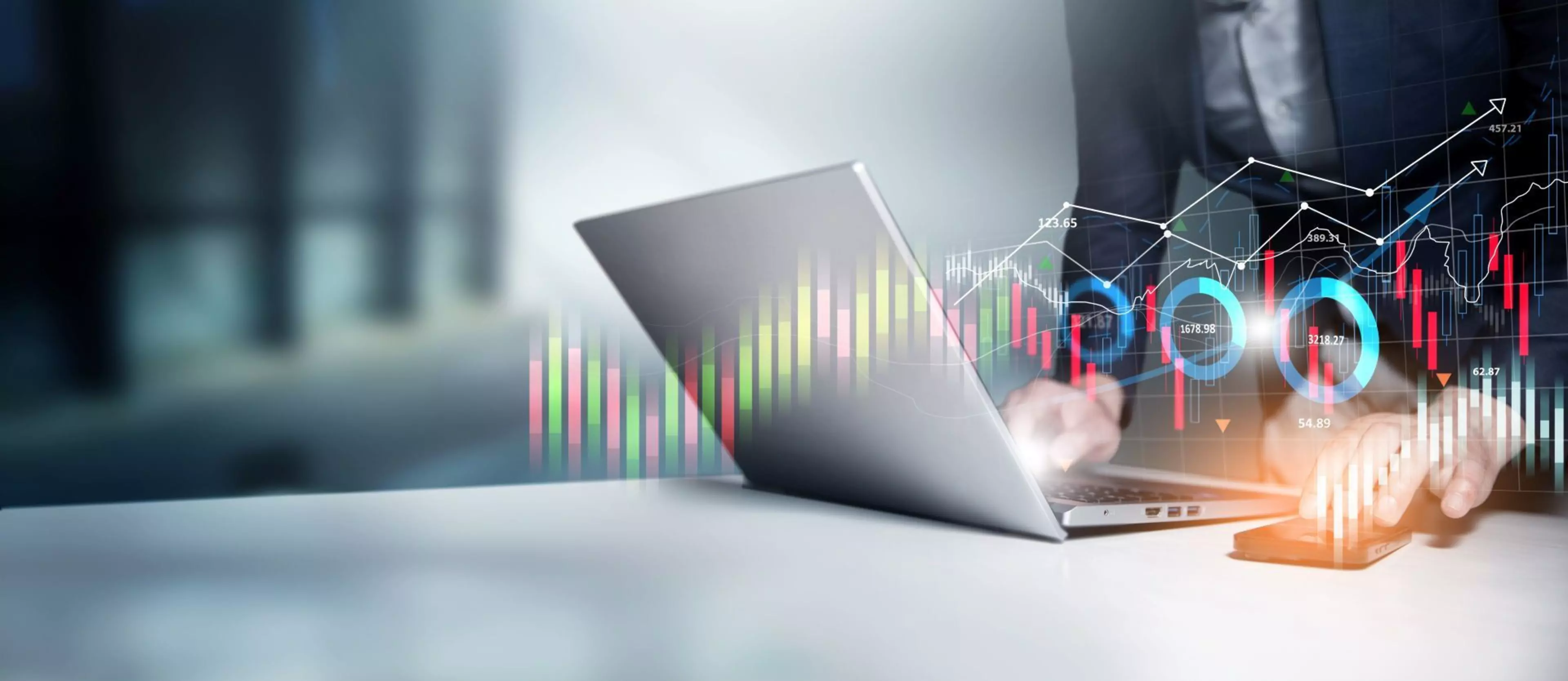 Laptop auf einem Schreibtisch, darüber visualisierte Datencharts und Diagramme mit Finanzkennzahlen und digitalen Analyse-Tools als Symbol für datenbasierte Geschäftsprozesse und Workflow-Automatisierung.