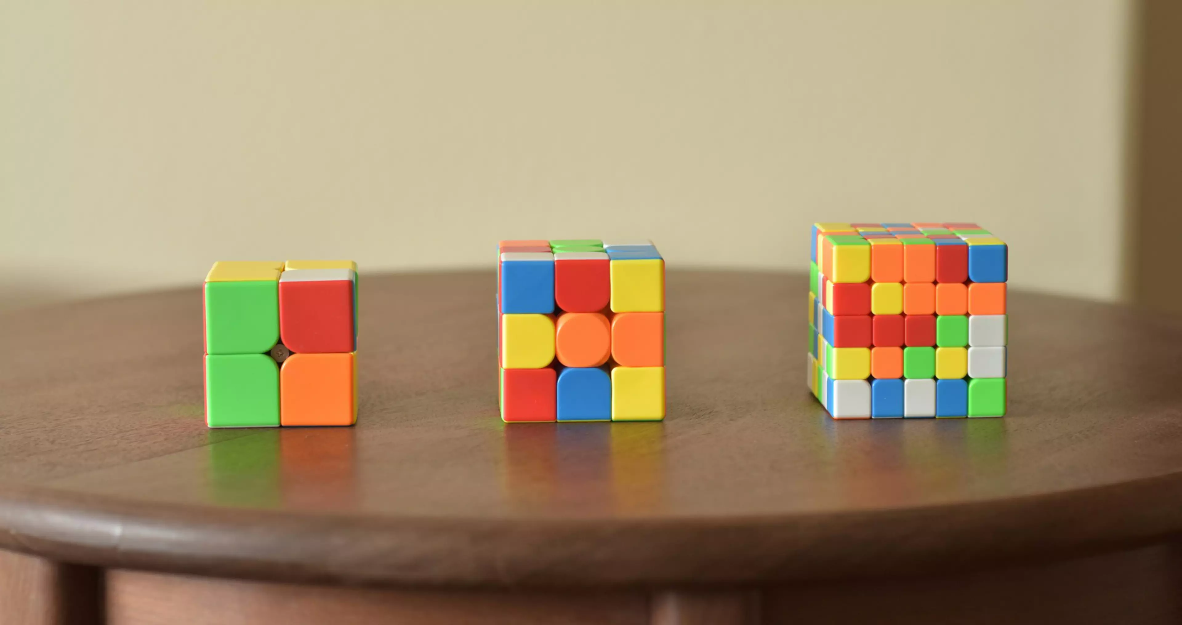 Tres cubos de Rubik diferentes (uno de 2x2, otro de 3x3 y otro de 5x5) sobre una mesa