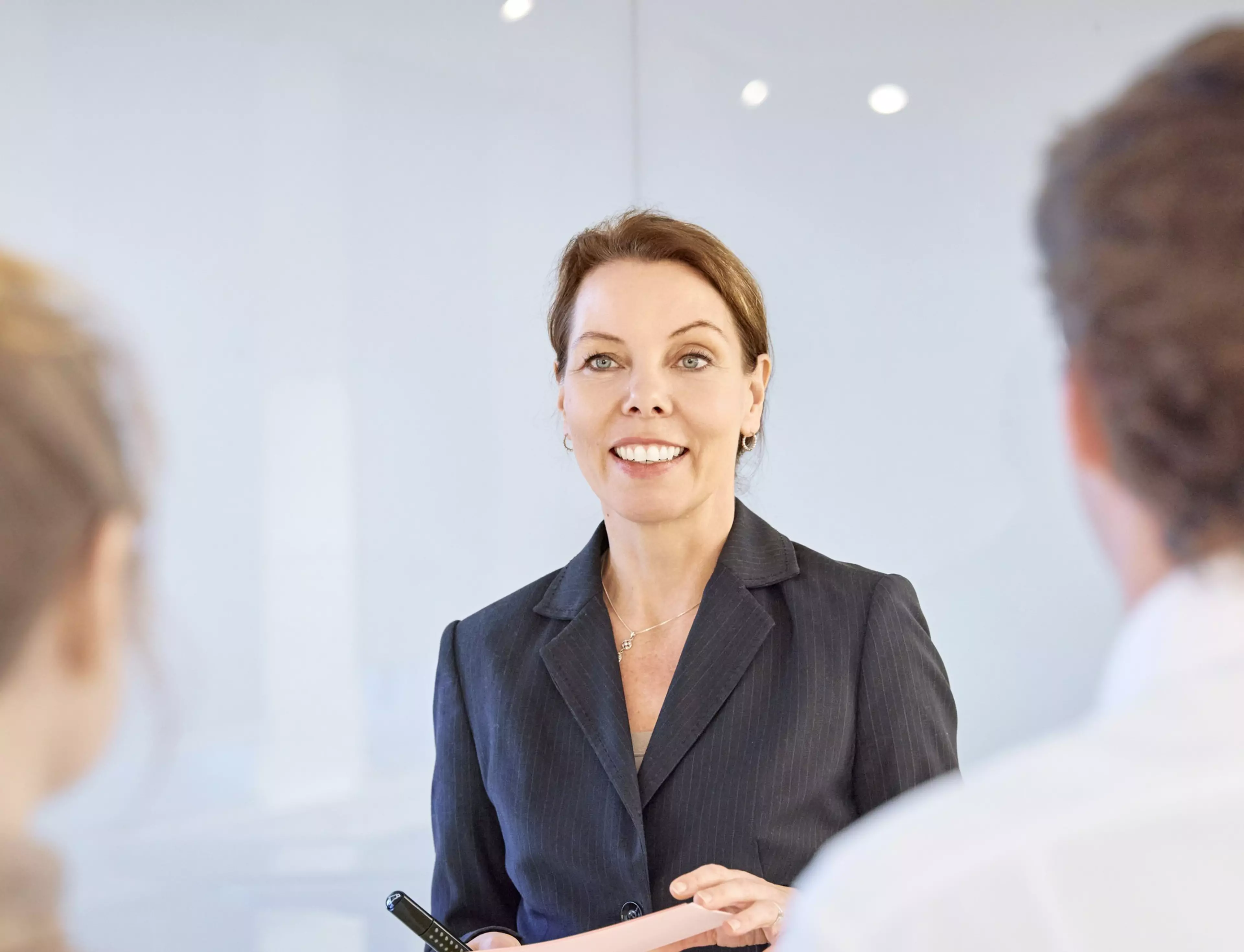 Britta Seidl-Bowe bei einer Präsentation in einem modernen Besprechungsraum, im Gespräch mit zwei Zuhörenden.
