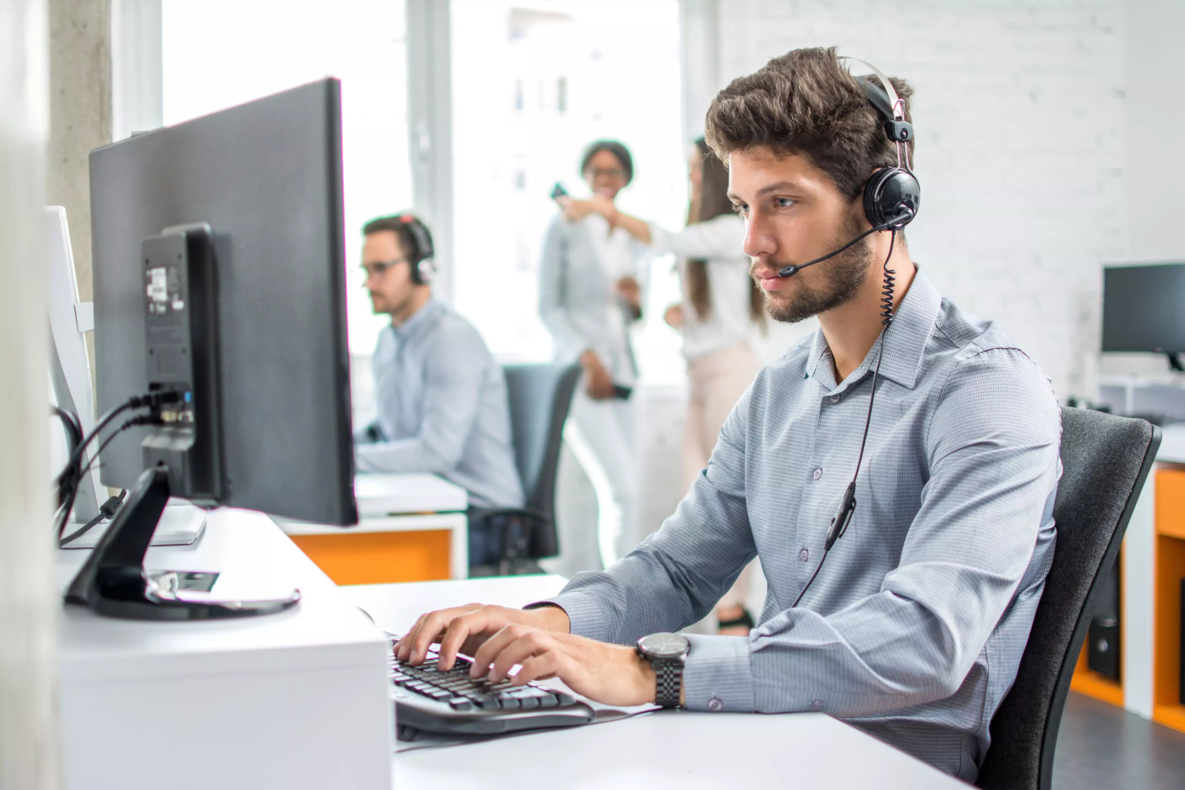 Un operador de helpdesk, con auriculares, atiende a un cliente de forma remota