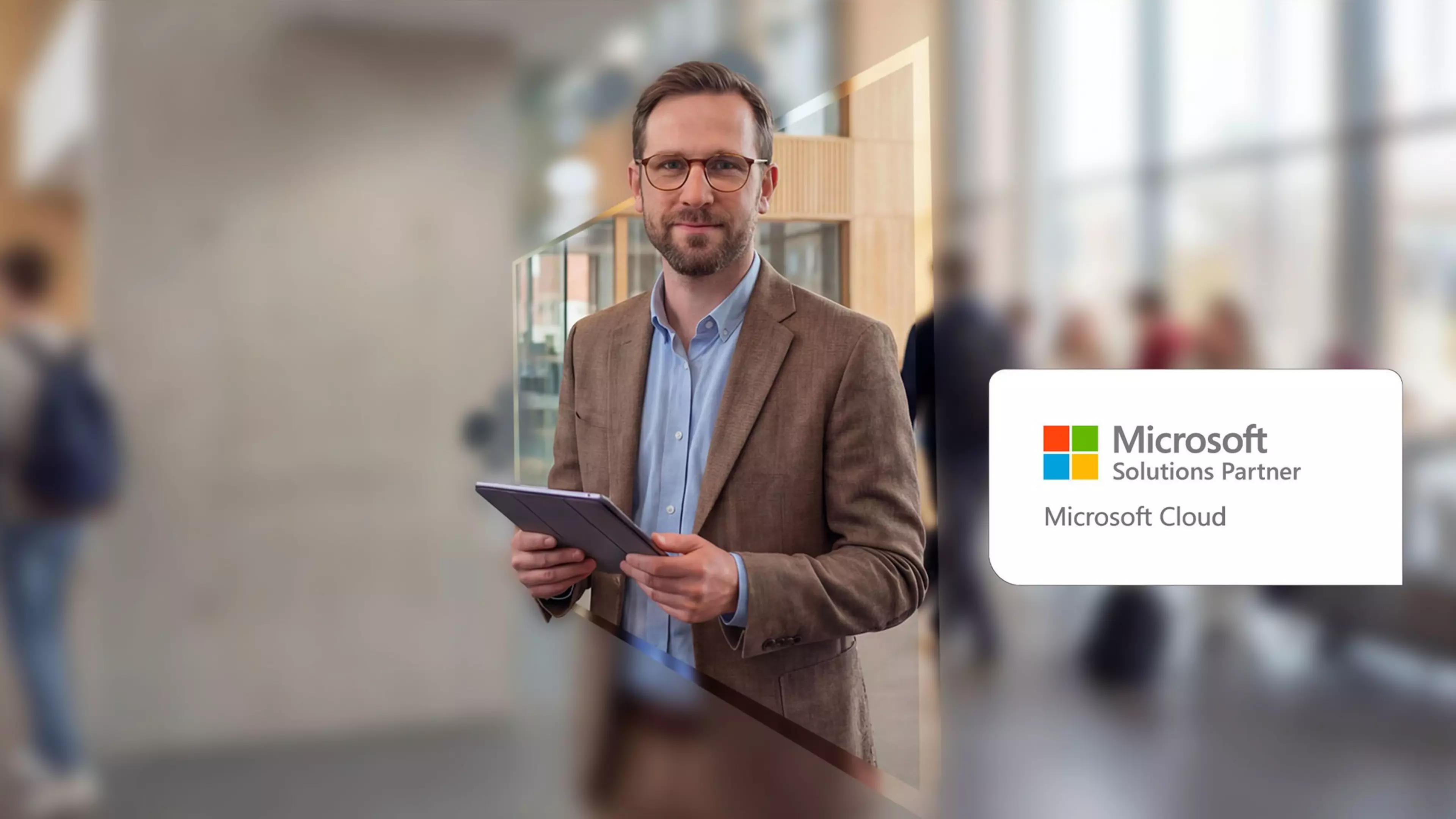 Un hombre en una oficina sostiene un tablet mientras mira a la cámara. Sobreimpreso, el logotipo de Microsoft Solutions Partner.