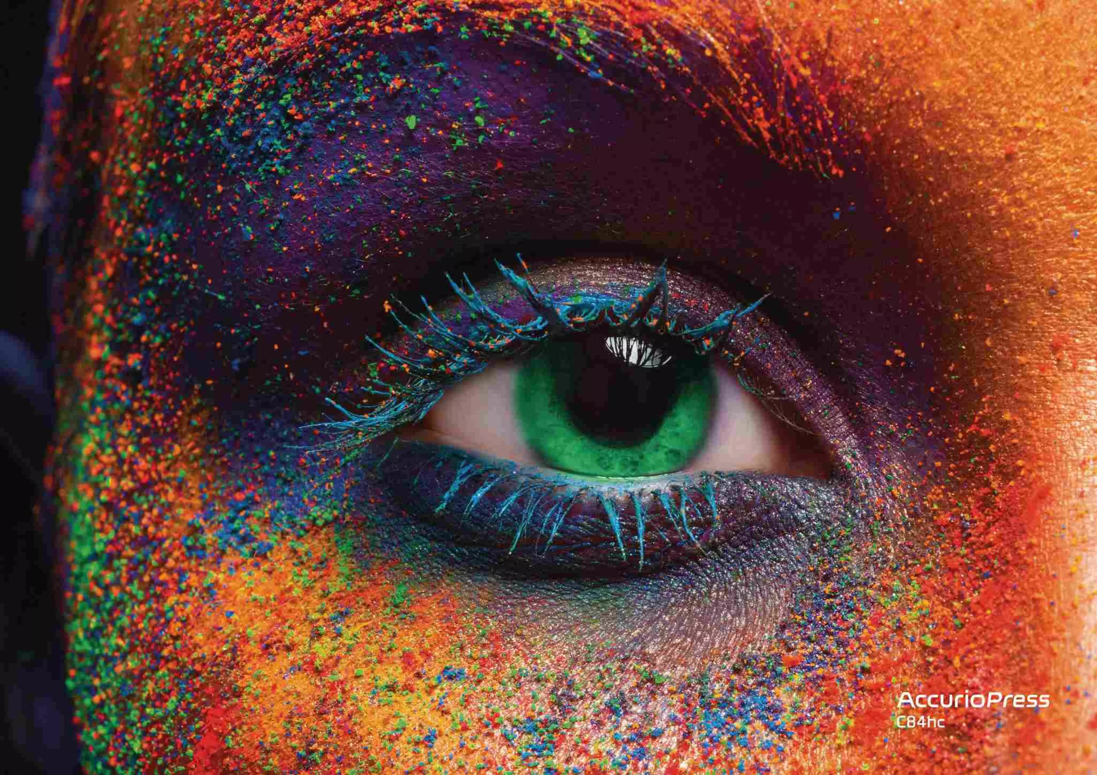 Detailed macro shot of a vibrant green eye surrounded by intense, vividly scattered color pigments in orange, blue, green, and red