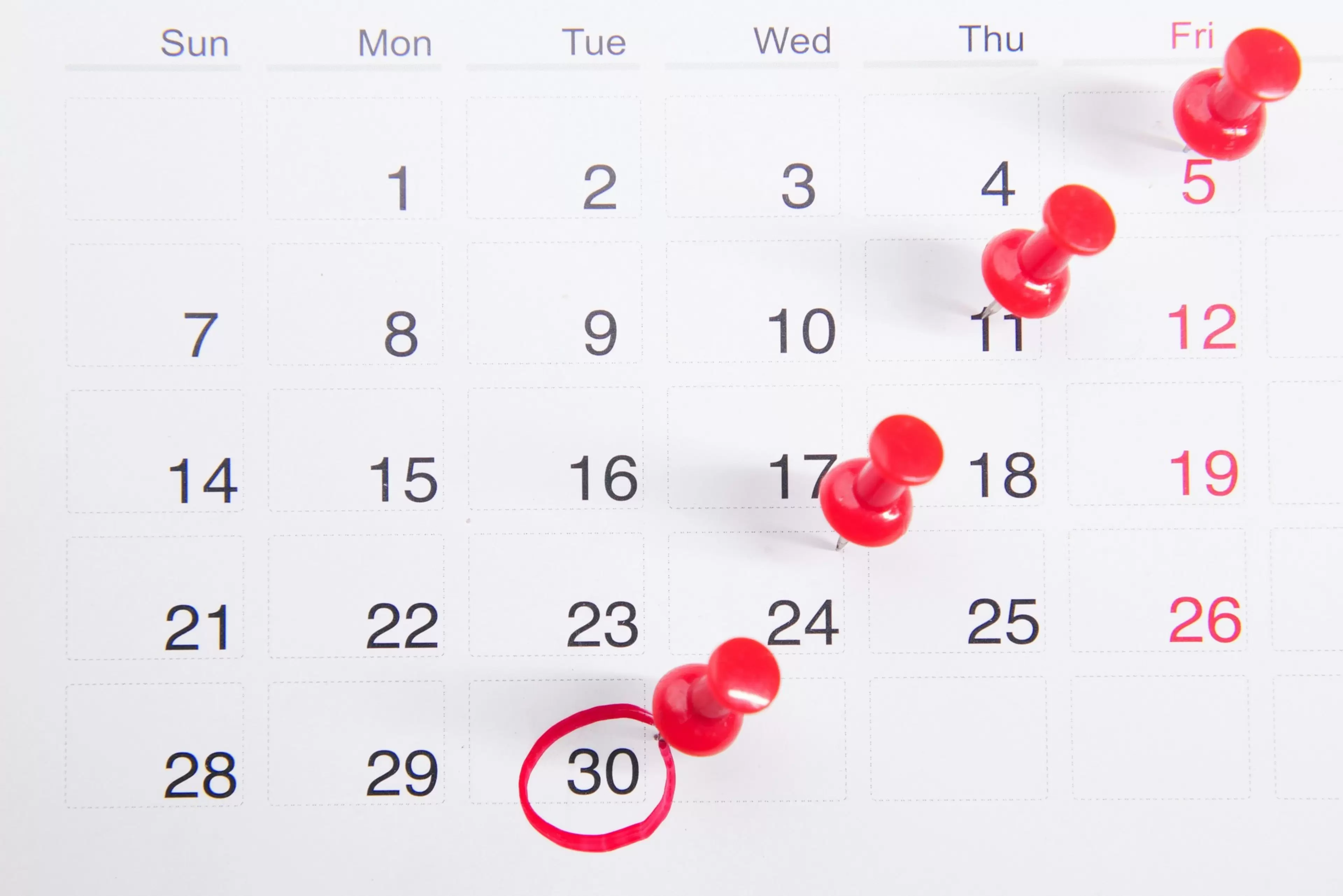 Calendario de pared con chinchetas rojas en algunos días