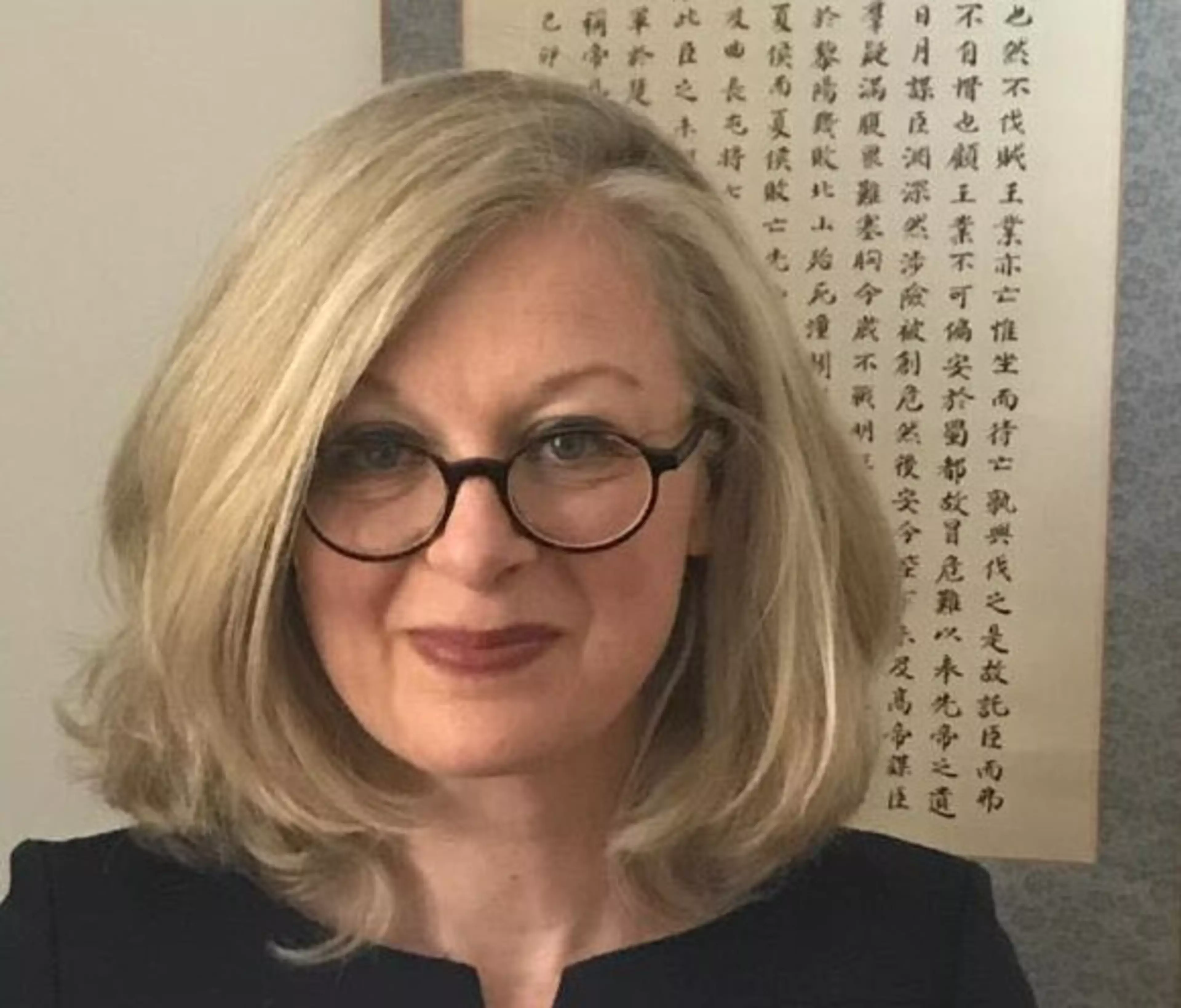 Delphine Hertel, Senior Specialist Diversity Management & Employer Branding bei Konica Minolta Europe, vor einer Wand mit chinesischer Kalligrafie.