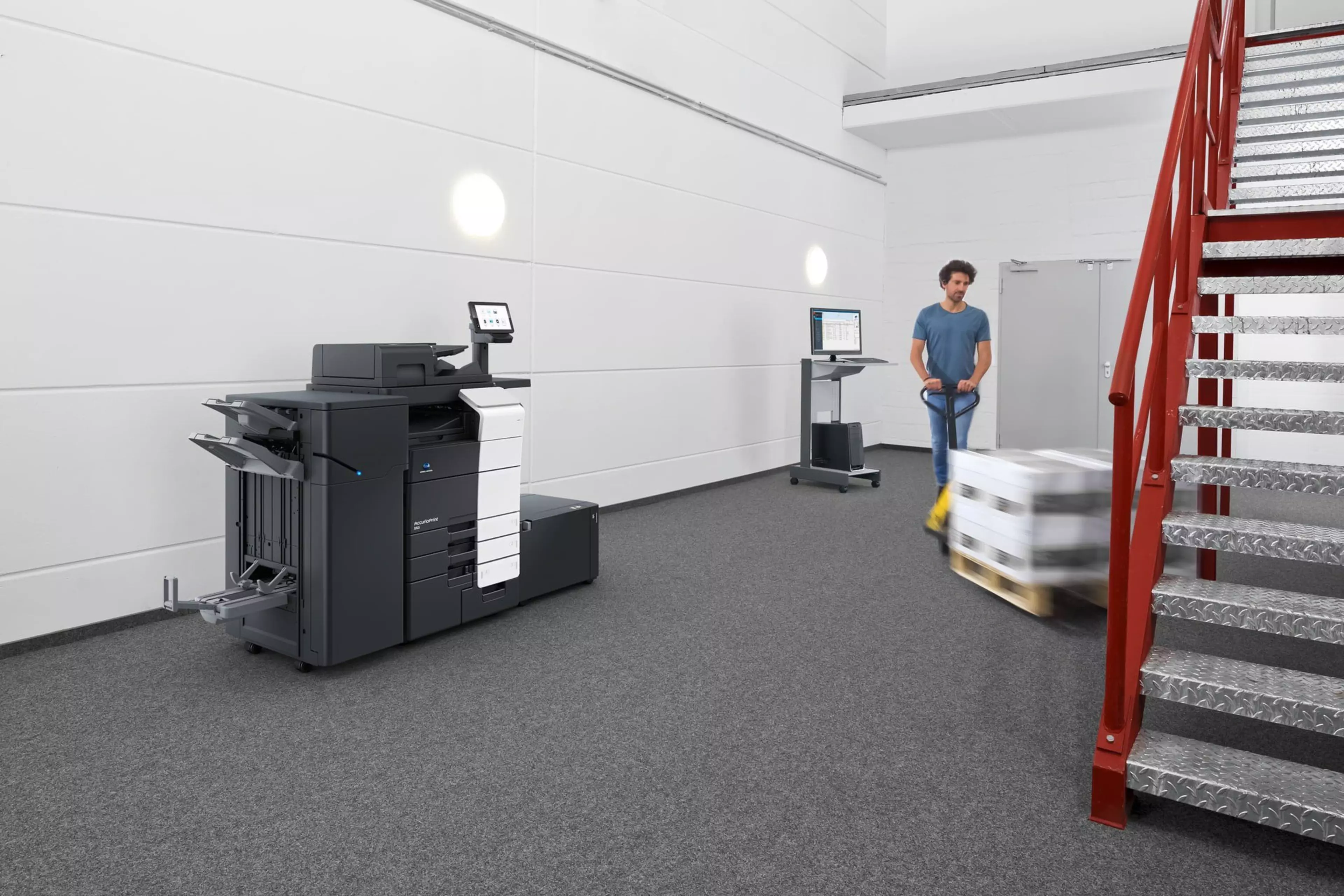 Taller de impresión con AccurioPrint 850i y operario trasladando un palet de papel