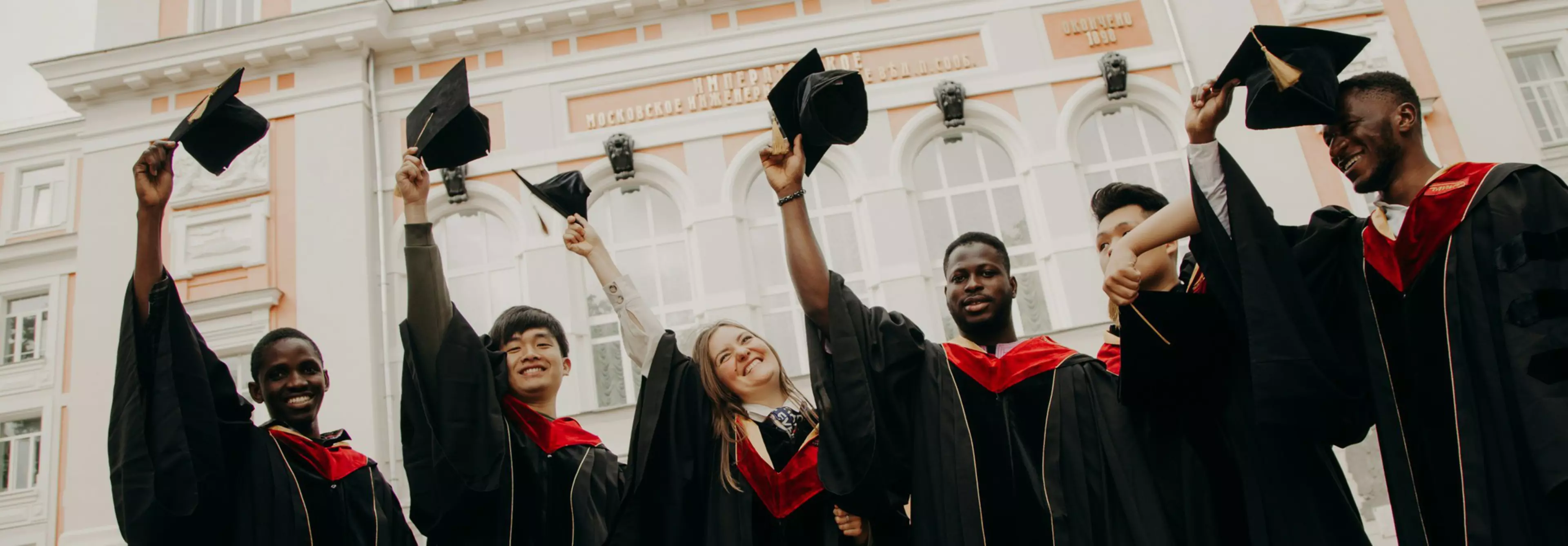 Estudiantes celebrando su graduación levantando sus birretes en el aire