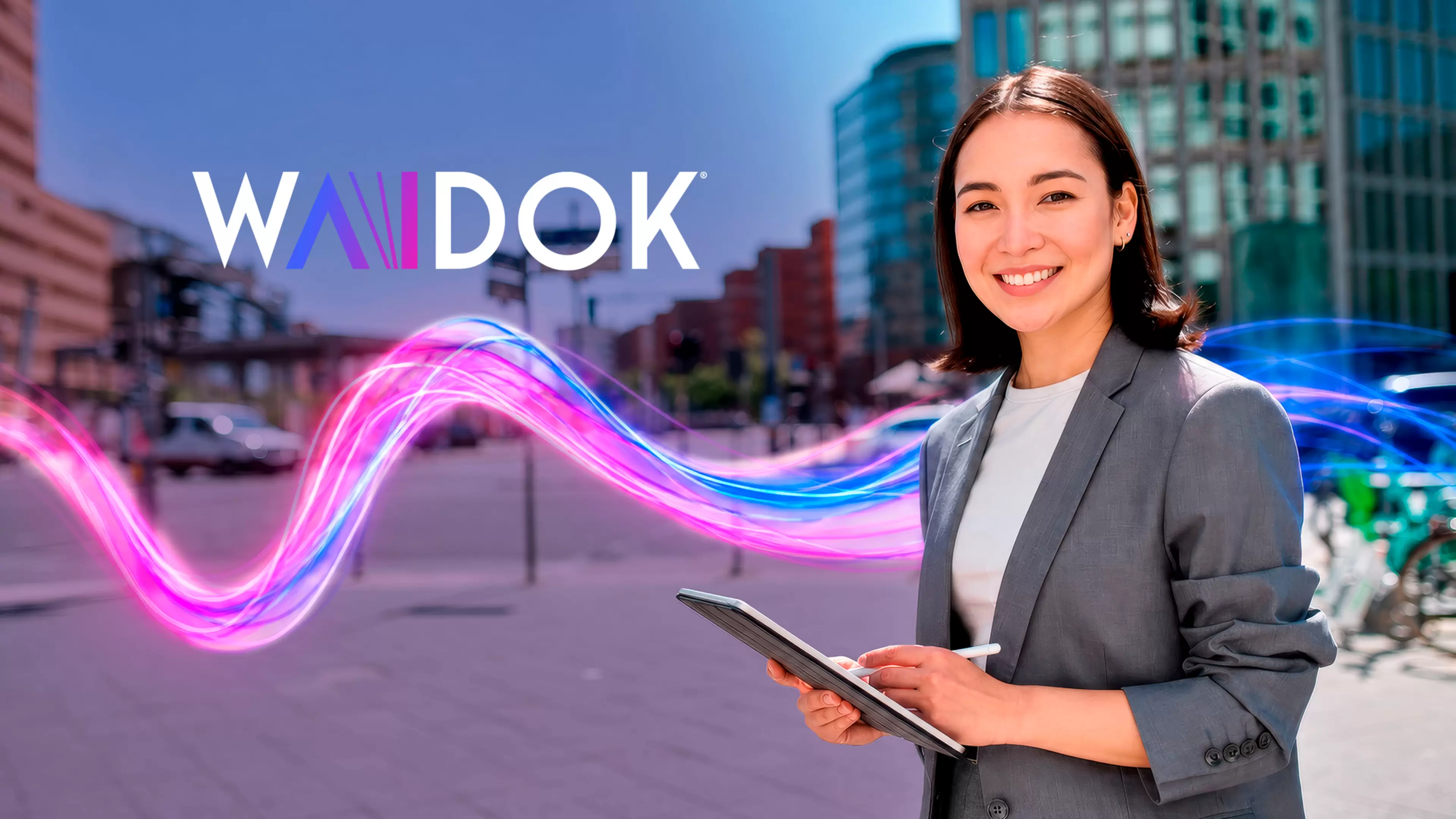 Mujer joven, sonriente, consulta su tablet. Sobre ella, logotipo de WAIDOK.