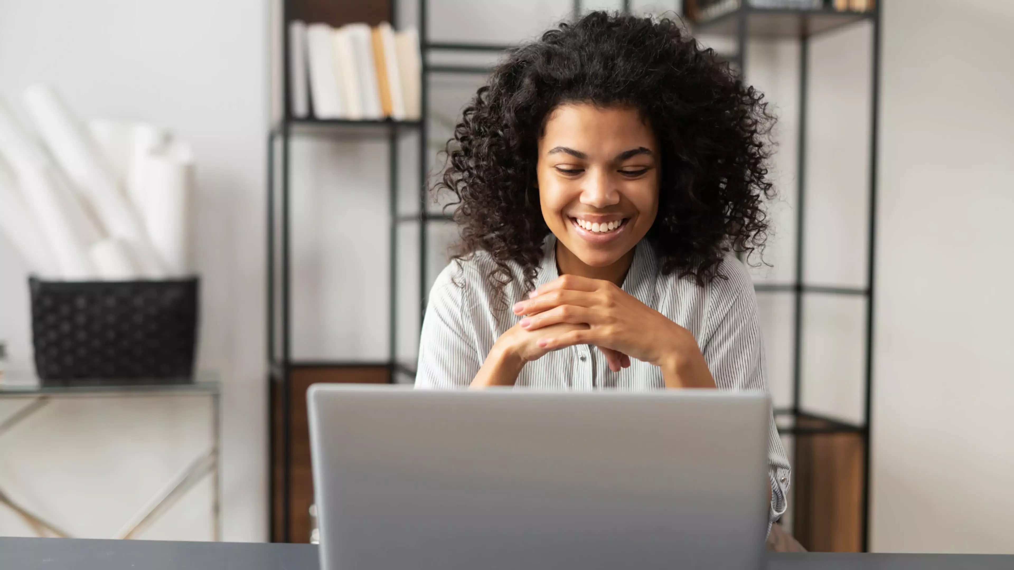 Mujer joven sonriendo, delante de un ordenador portátil