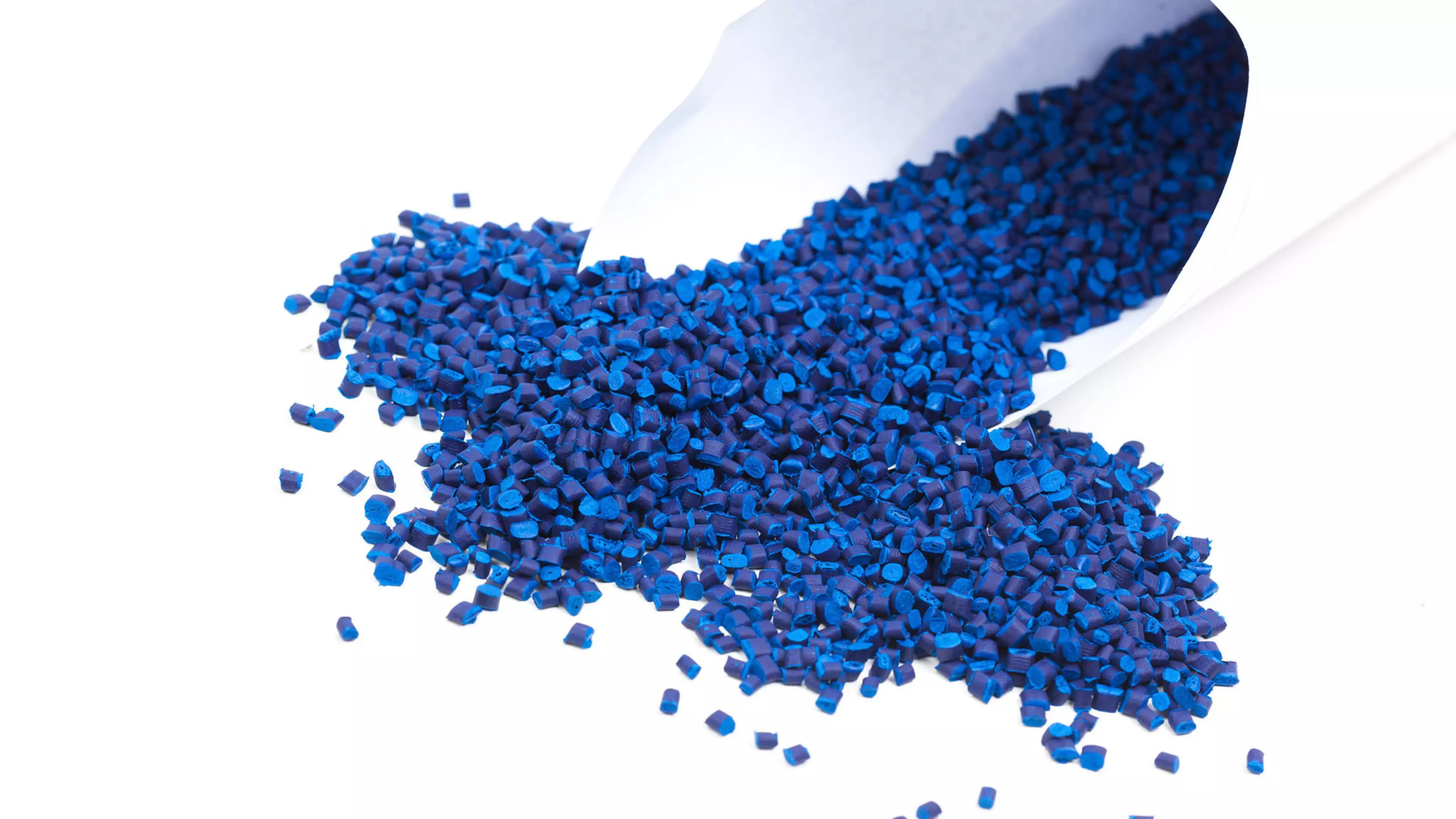 Pellets de material reciclado de color azul intenso se desbordan de un cucurucho de papel
