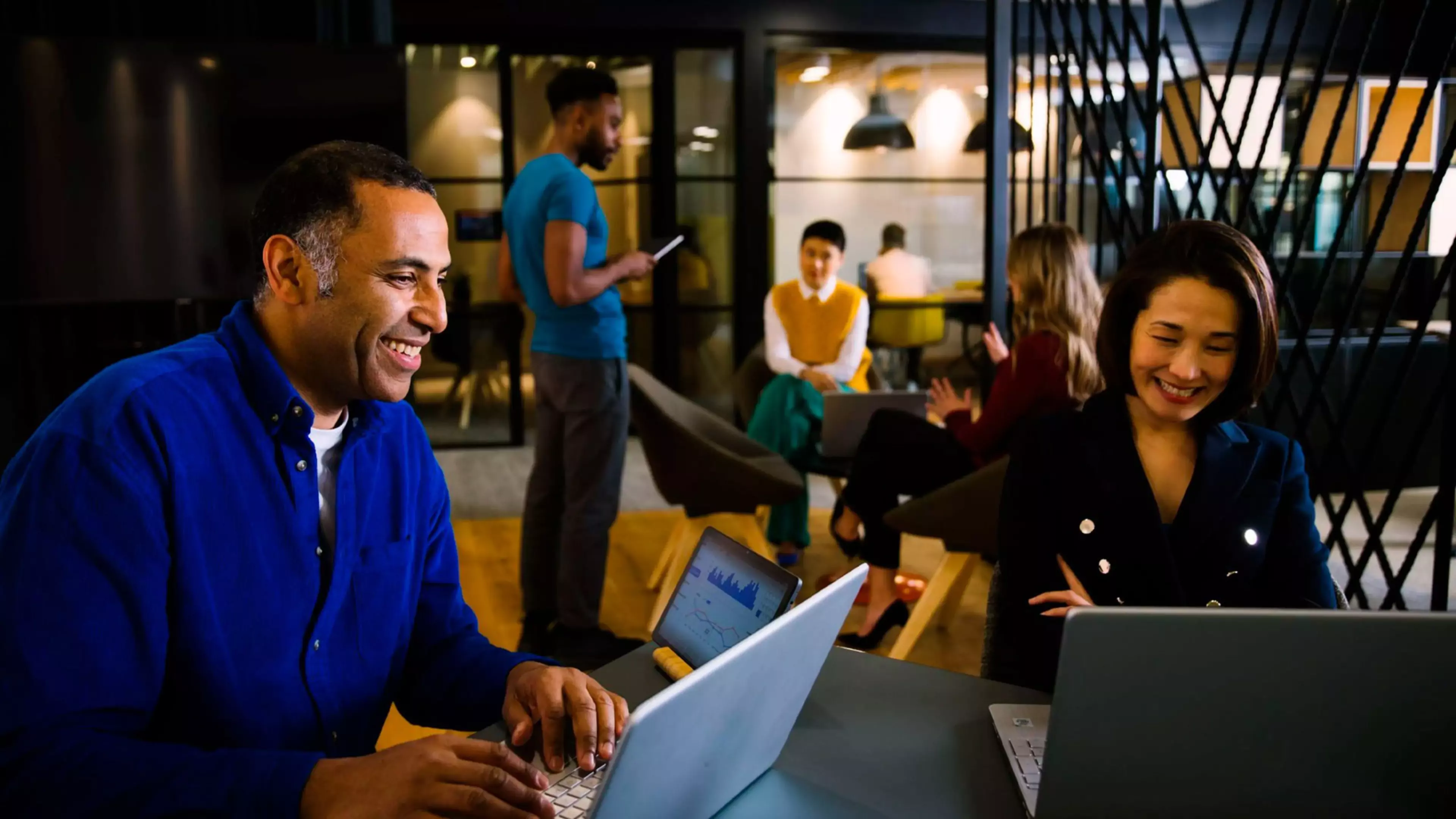 Un hombre y una mujer trabajan en una oficina, frente a sus ordenadores portátiles