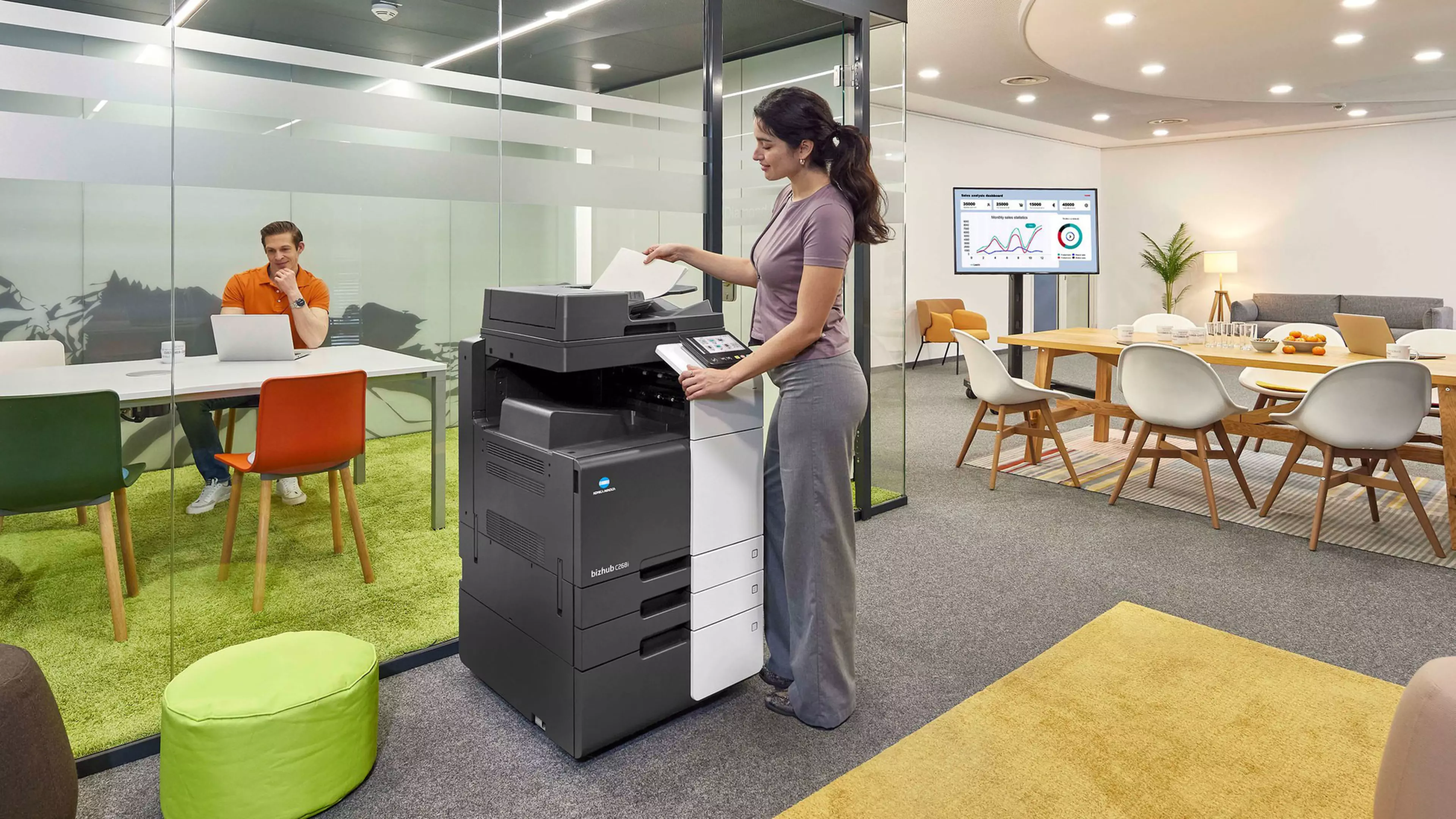 En una oficina, una empleada imprime documentos en una multifuncional Konica Minolta bizhub C268i