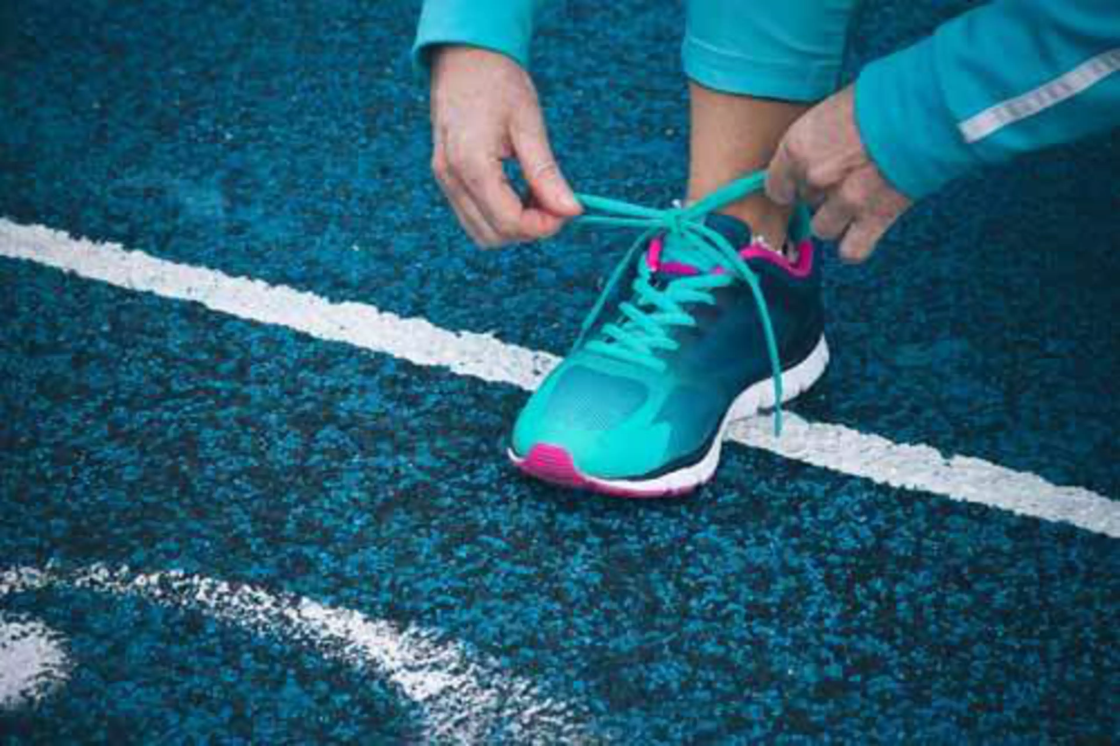 woman tying the shoelaces on running track