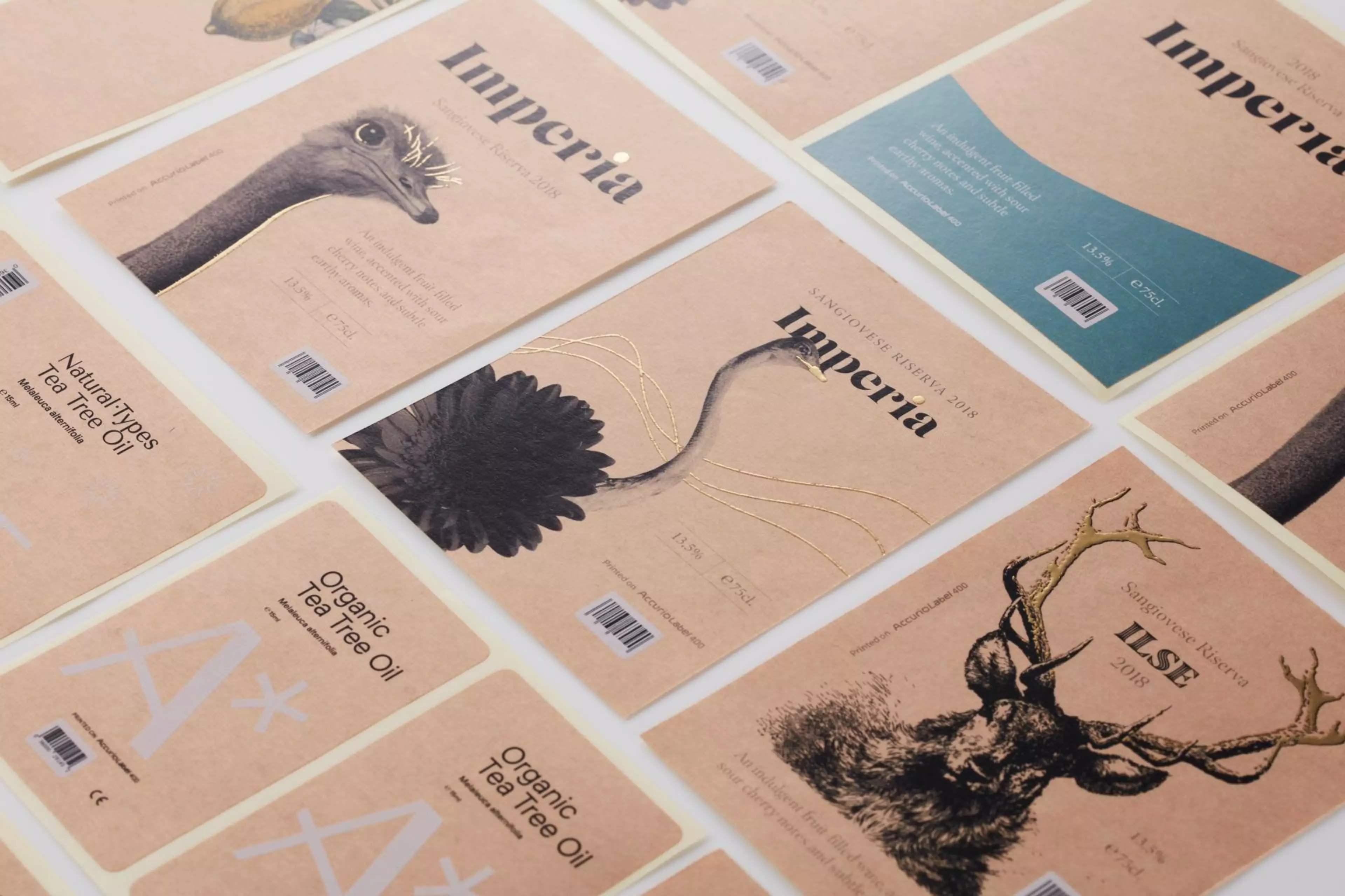 Verschiedene hochwertige Produktetiketten auf braunem Naturpapier, darunter Weinetiketten und Verpackungslabels mit minimalistischen Designs, Goldakzenten und Tierillustrationen.