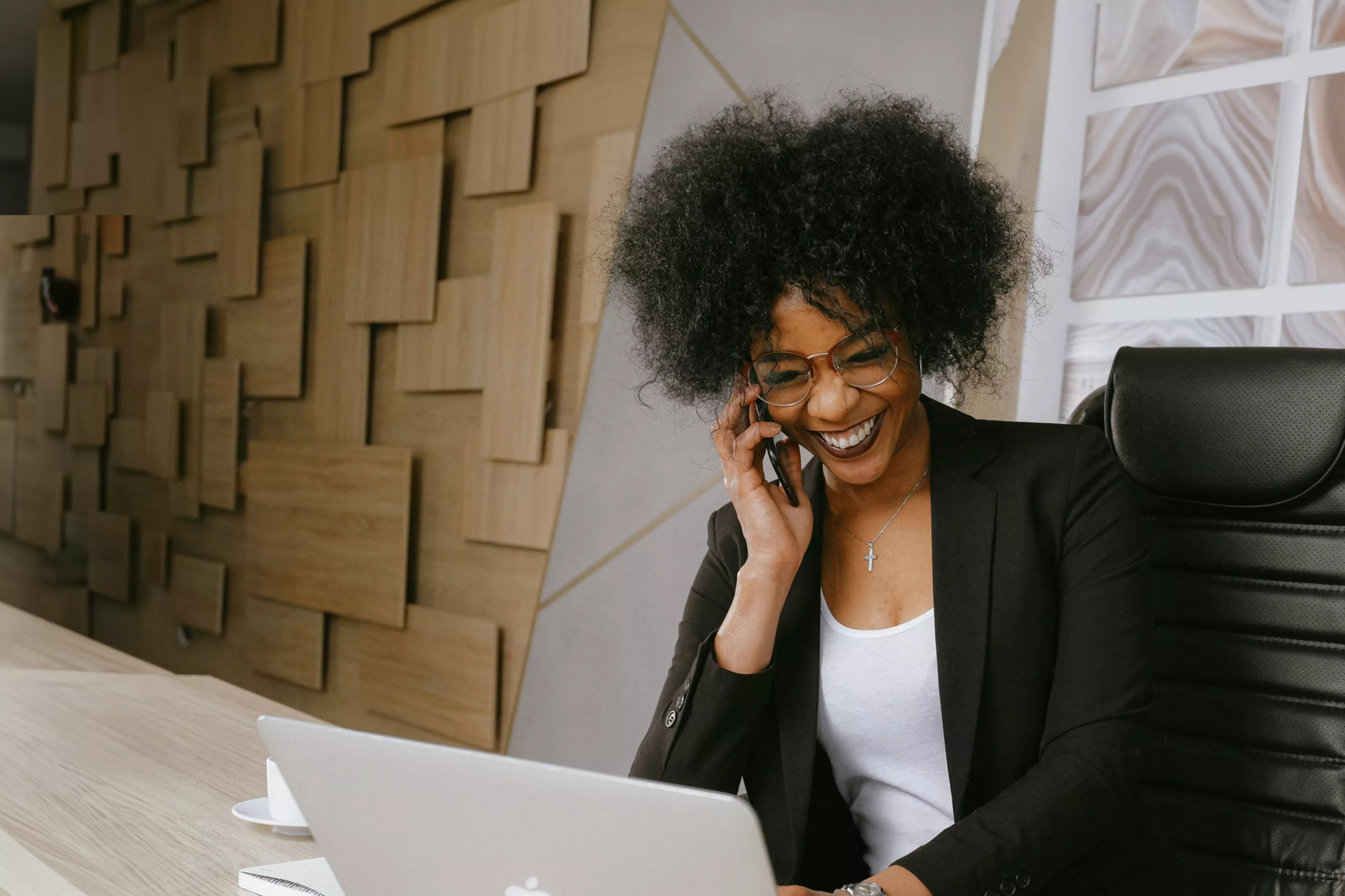 Mujer joven frente a un ordenador portátil y hablando por teléfono