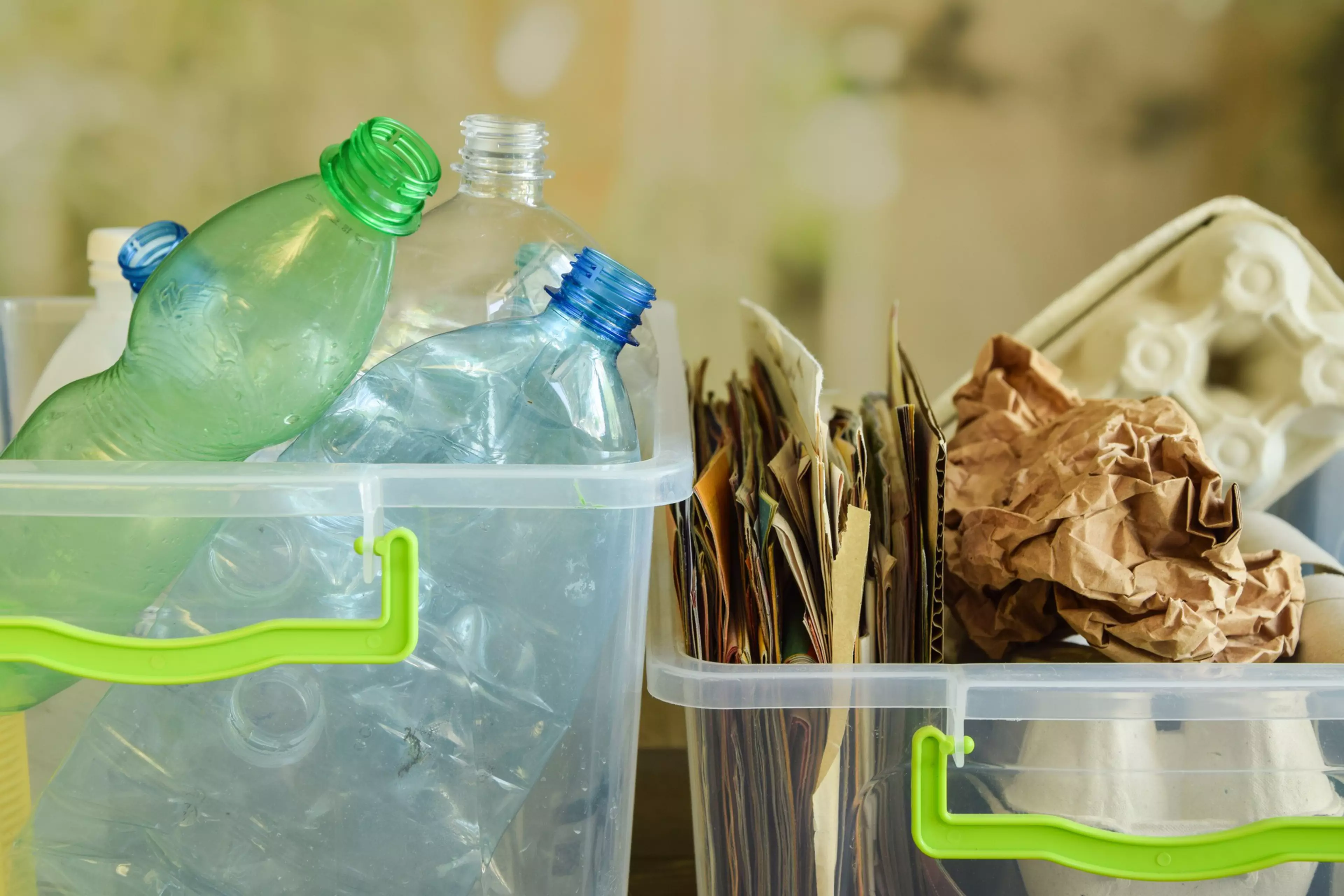 Dos contenedores con diferentes elementos para reciclar: botellas de plástico y papel