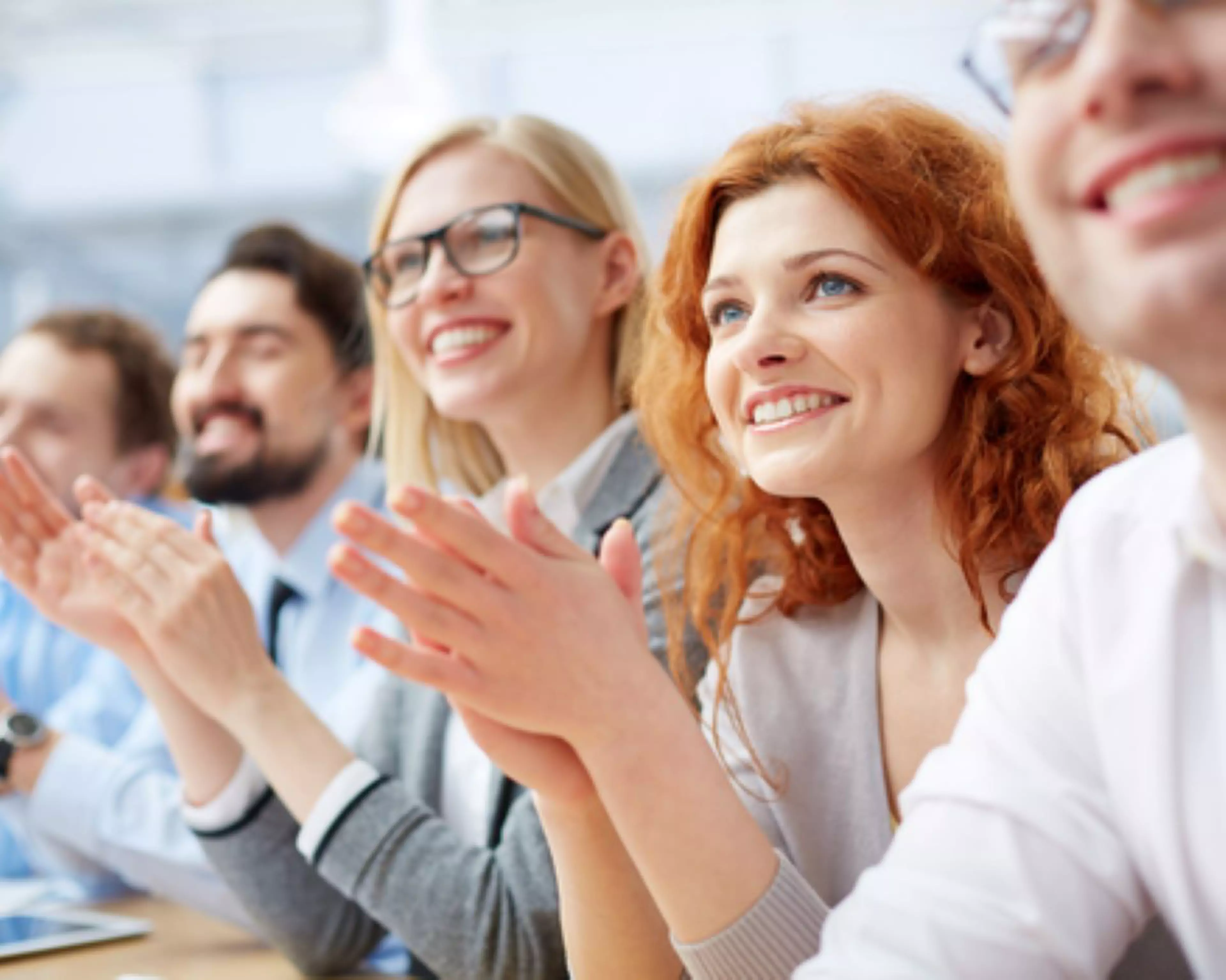 Lächelnde Personen applaudieren in einem Meeting – Ausdruck von Anerkennung, Wertschätzung und positiver Teamdynamik
