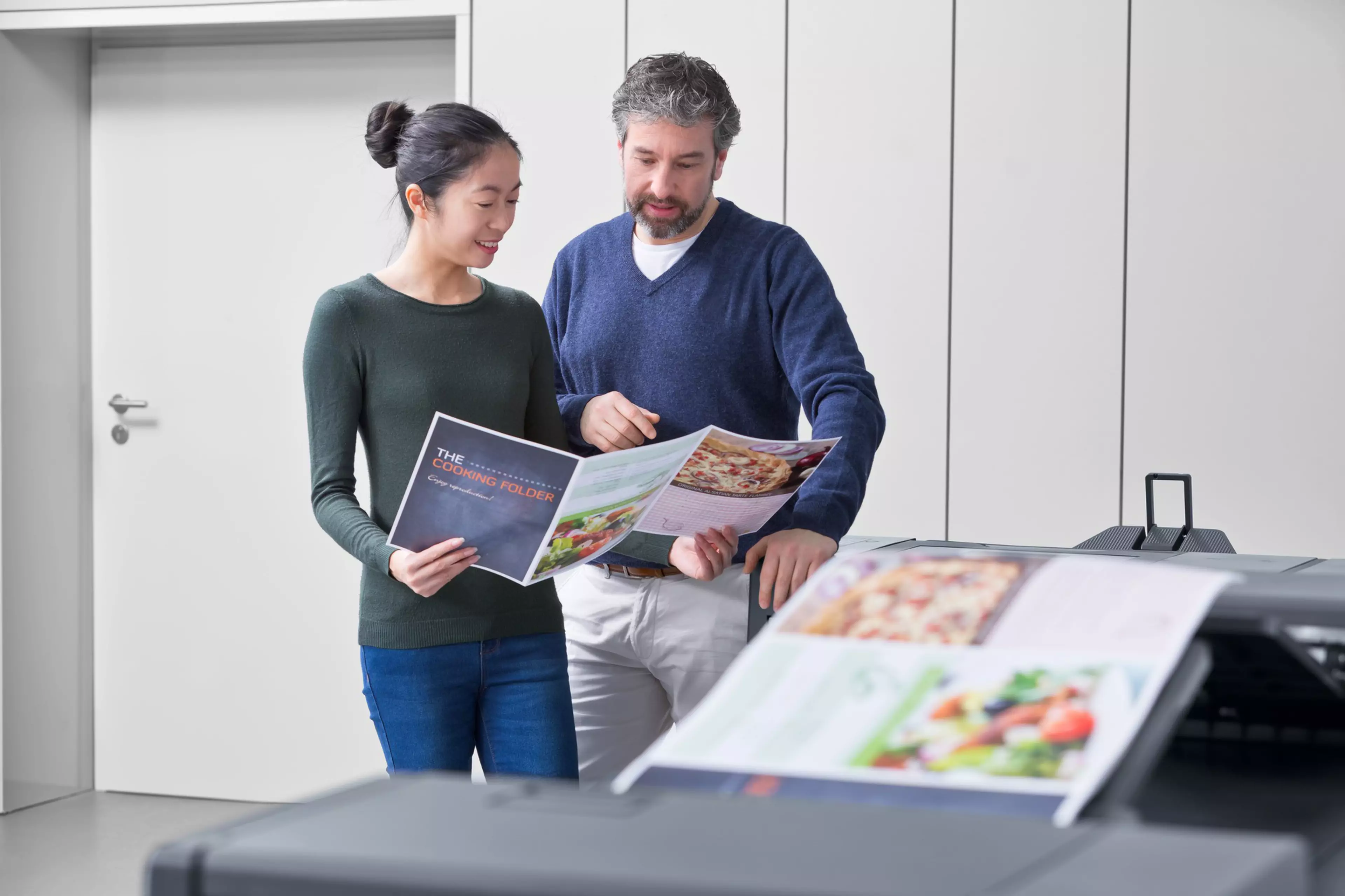 Dos trabajadores de un taller de impresión observando la calidad de las impresiones