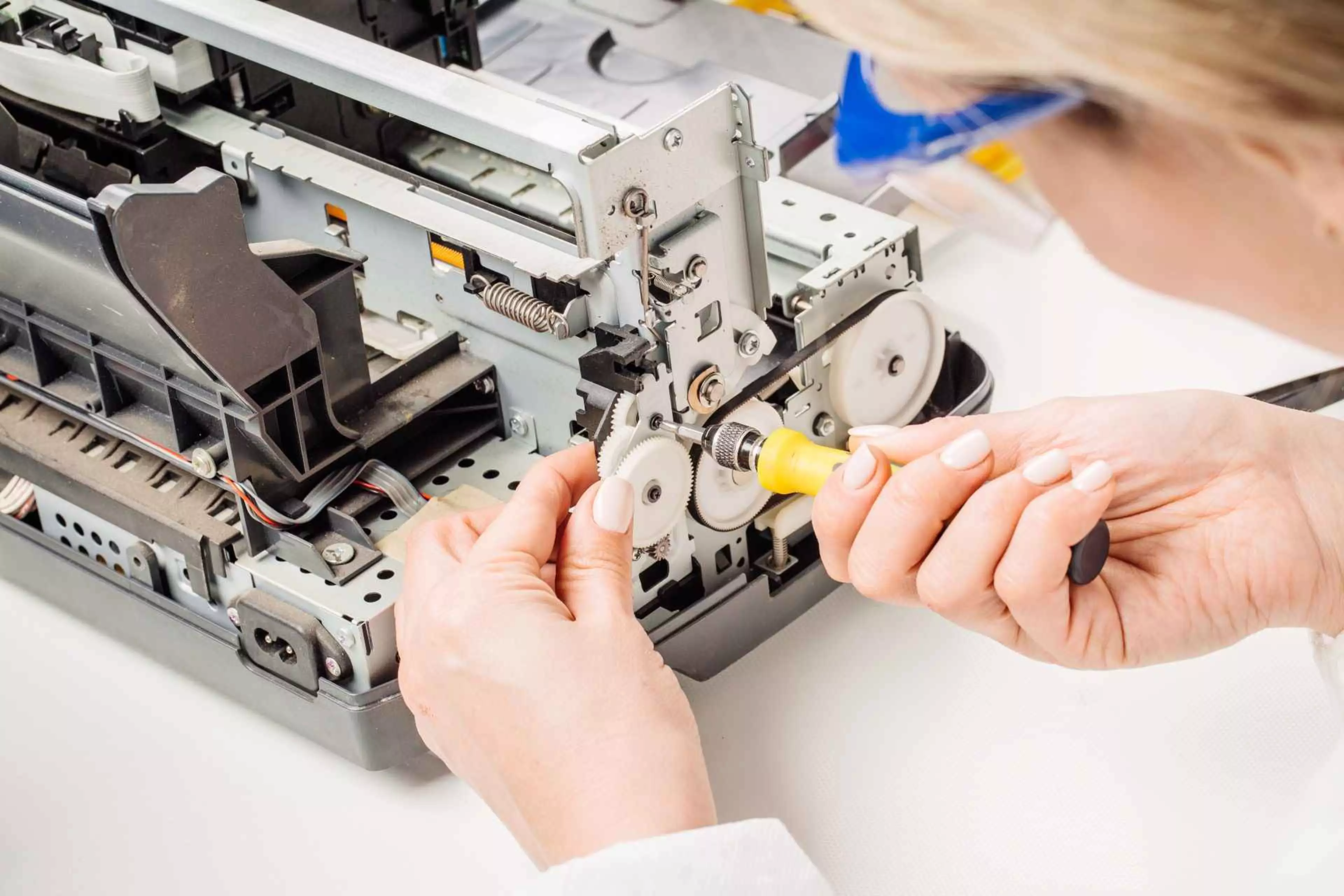 Technikerin repariert die Mechanik eines Büro-Druckers im Rahmen des Refurbishing-Prozesses