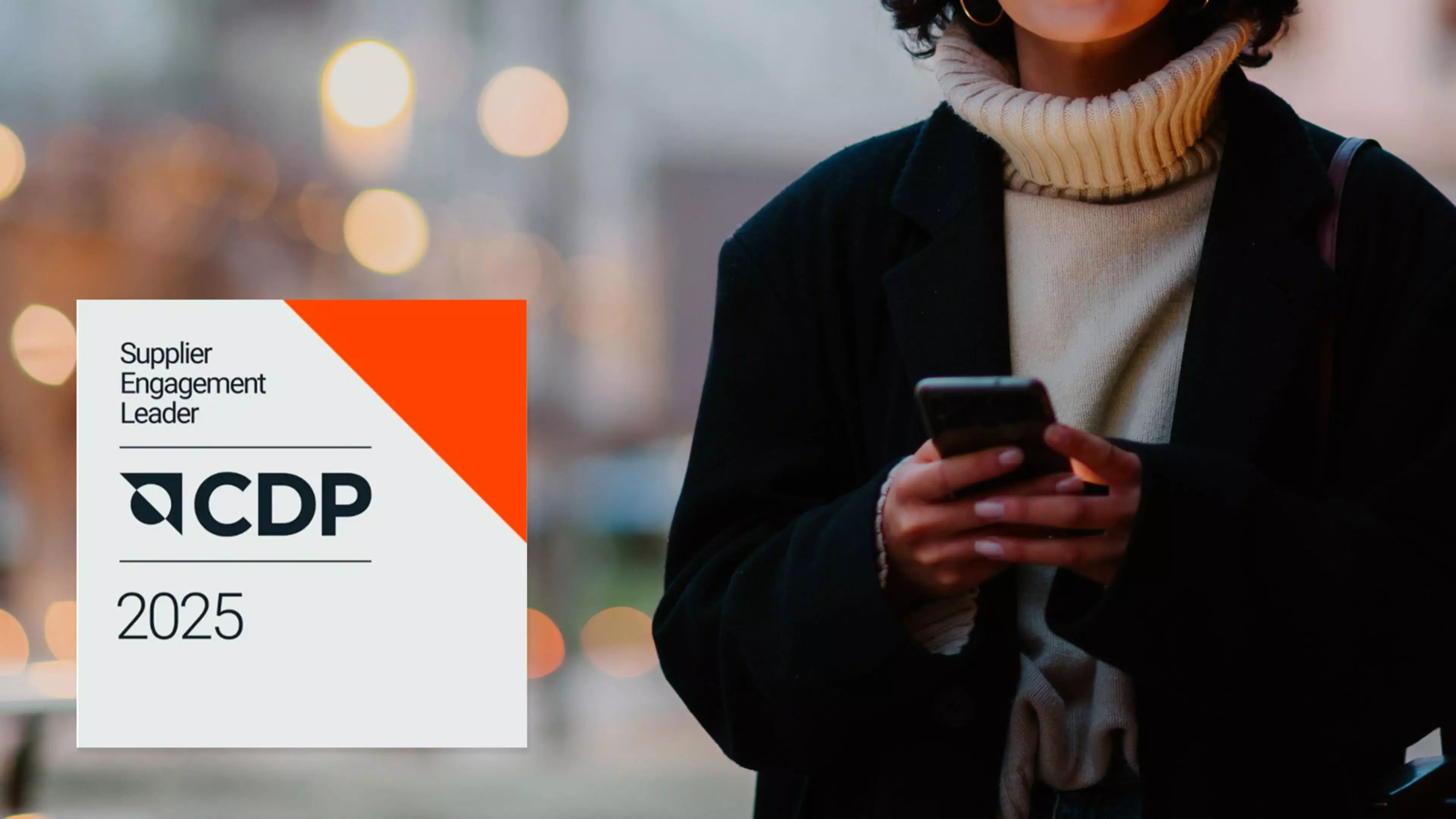 Una mujer joven mira su teléfono móvil. Sobreimpresionado, el logo de Supplier Engagement Leader CDP 2025.
